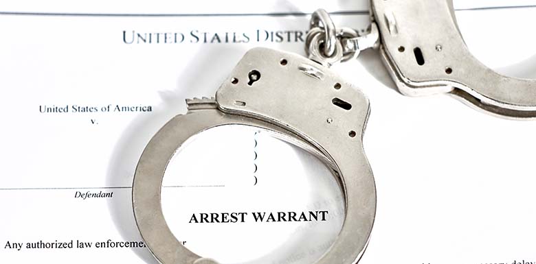 Arrest warrant paper with handcuffs on top