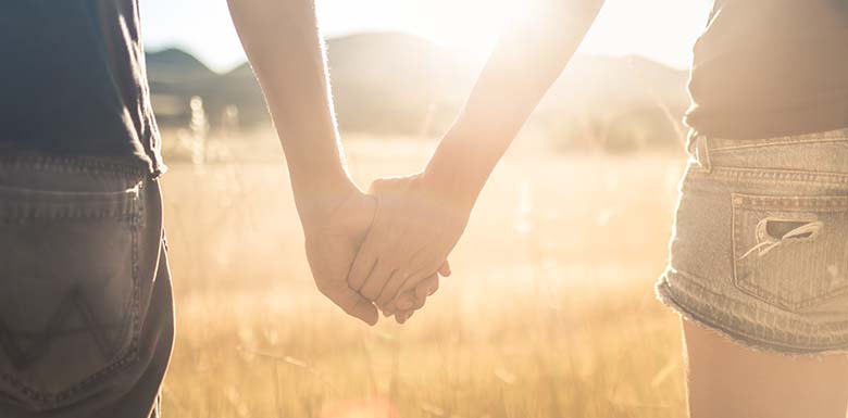 Teen couple holding hands in field