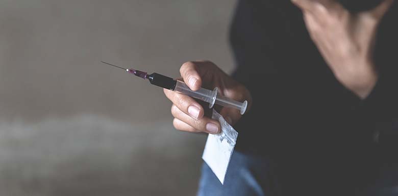 Person holding needle full of drugs